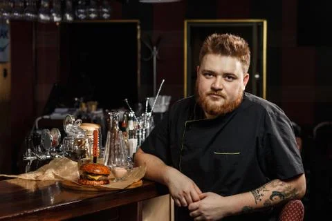 Chef in black uniform presenting a tray with burger Fotos Stock