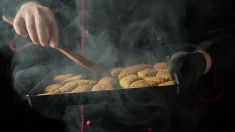 Chef in black uniform removes freshly baked cookies from oven tray, using wooden Stock Footage 334720351