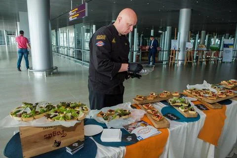 Chef in black uniform serving snacks on table for degustation in Lviv airport Stock Photos