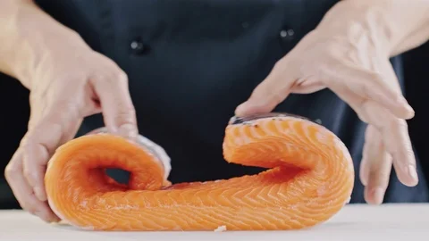 Chef in black uniform Unrolling nice big slice of red salmon fish Stock Footage 104719965