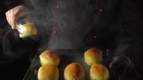 Chef in black uniform uses tongs to lift freshly baked golden rolls from a tray, Stock Footage 335241487
