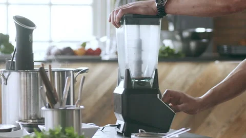 Chef blending herbs in a blender in interior kitchen with soft day lighting. Clo Stock Footage 199459936