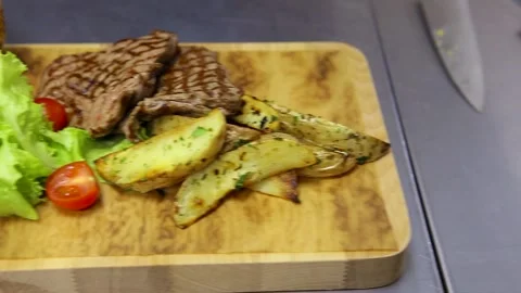 A chef in blue gloves lays the cobs of fried corn on a wooden plate. On the dish Stock Footage 130903760