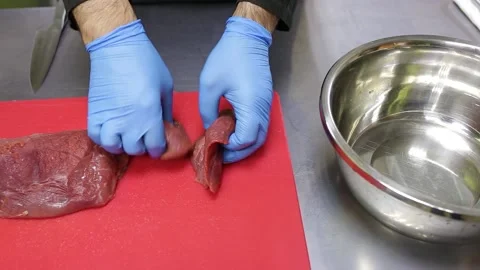 A chef in blue gloves puts raw meat with a red chopping board in a shiny metal b Stock Footage 130903727