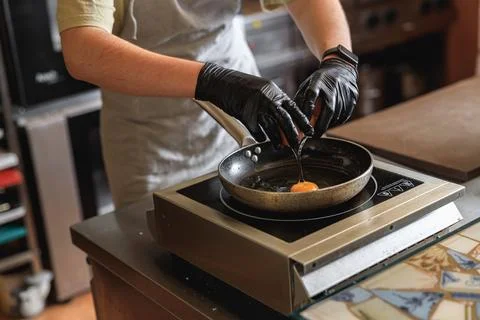 Chef break an egg on a frying pan to make delicious breakfast. Working Stock Photos