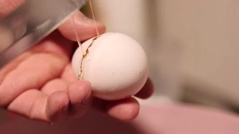 Chef breaks chicken egg with knife and yellow yolk falls into pink bowl Stock Footage 332574065