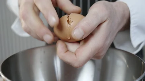 Chef breaks chicken eggs into a silver bowl. Stock Footage 233714929