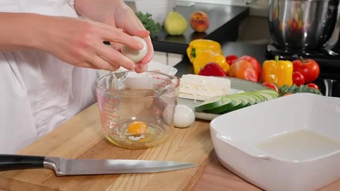 The chef breaks eggs into a glass measuring cup on a wooden board Stock Footage 264141783