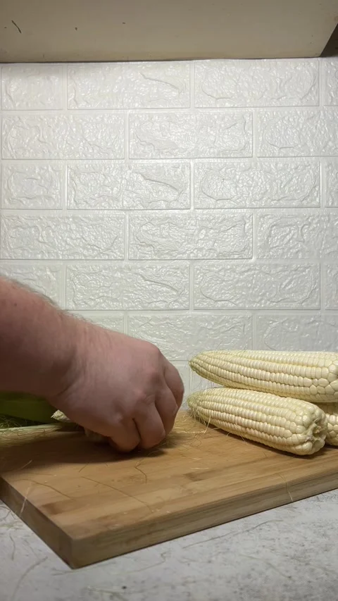 Chef breaks fresh raw cob of white corn in half. Front view Stock Footage 289034176
