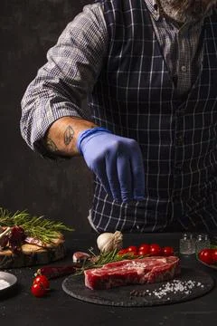 The chef brushes salt over the ready-to-grill beef entrecote Stock Photos