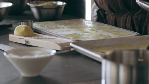 Chef brushing egg wash over slices of potato on a tray in interior kitchen with Video stock 199457199