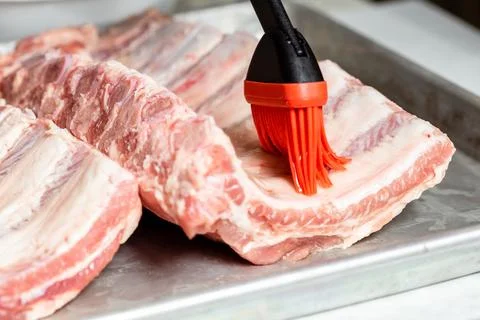 Chef brushing raw beef ribs with marinade Stock Photos