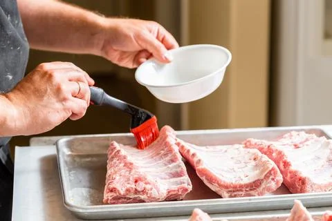 Chef brushing raw beef ribs with marinade Stock Photos