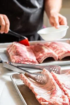 Chef brushing raw beef ribs with marinade Stock Photos