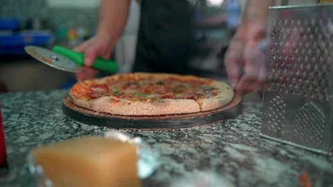 The chef at the cafe slices pizza on the table in close-up. Slow motion video. Video stock 231336770