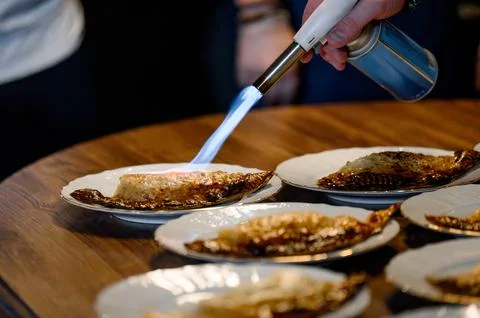 Chef caramelizing dessert with kitchen torch on plates at restaurant Stock Photos
