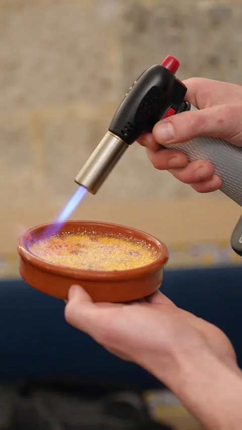 Chef caramelizing the top of a crme brle using a culinary torch in a gourme.. Stock Footage 310051268