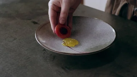 Chef carefully placing slices of beets onto a plate in interior kitchen with sof Stock Footage 199462941
