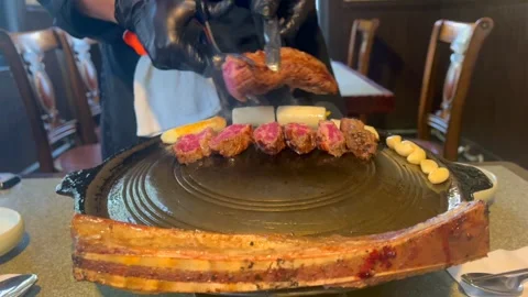 Chef carefully slices thin slices of marbled beef with scissors on hot grill Stock Footage 301517184