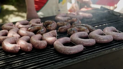 Chef caterer BBQ's large pork spicy sausages over smoking hot plate Stock Footage 193370329