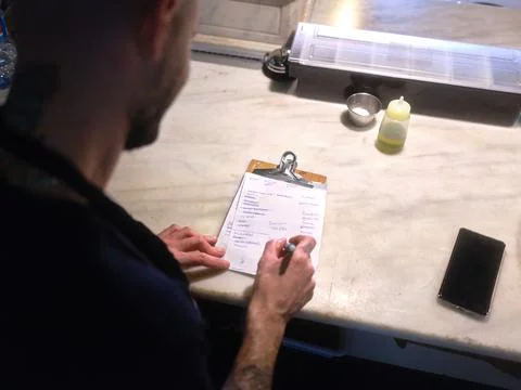 Chef checking the list to do written on a piece of paperr in the kitchen Stock Photos