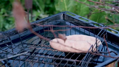 Chef checking raw sausages on grill in slow motion Stock Footage 284044761