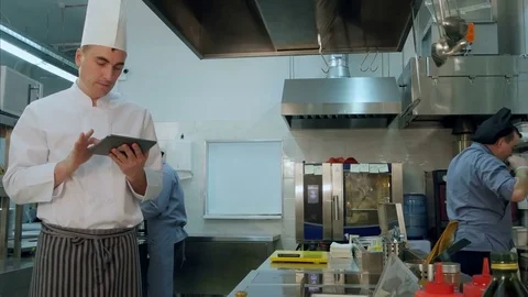 Chef checking up recipes on digital tablet in the professional kitchen Видео 72323802