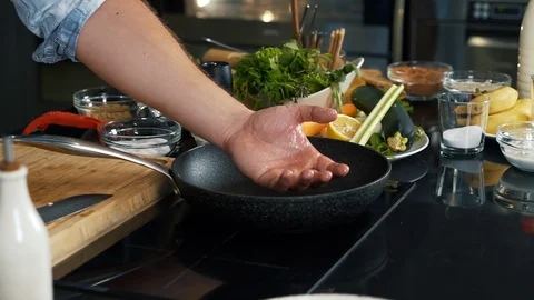 Chef checks back of hand for degree of heating of pan on stove, fries meat Stock Footage 123352954
