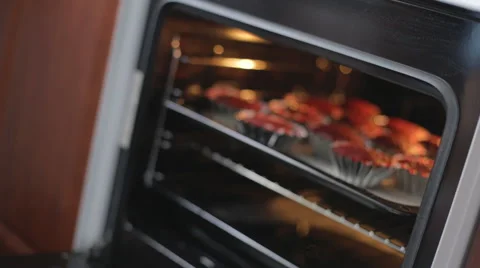 Chef checks on the readiness of cupcakes in ovens Stock Footage 53332653