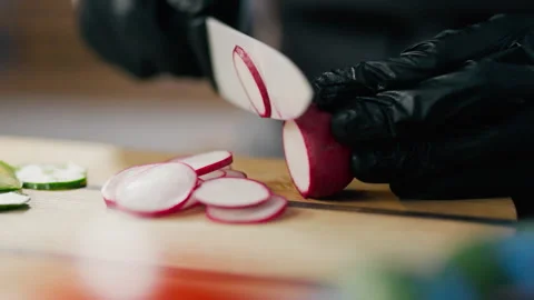 Chef chef slowly cuts radish vegetables into a sandwich at the chef's workpl Stock Footage 247399559