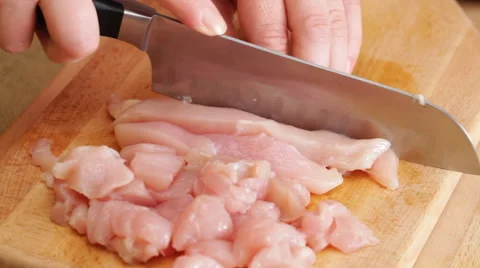 Chef chopping chicken brests onto cubic chunks, closeup Stock Footage 56346118