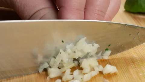 Chef chopping fresh garlic cloves on a wooden cutting board. 库存影片 342280414