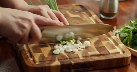Chef chopping fresh herbs spring onions, parsley, and dill on a wooden cutting Stock Footage 318419934