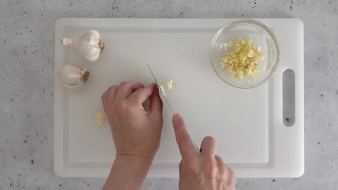 The chef chopping garlic on a white plastic cutting board Stock Footage 256758178