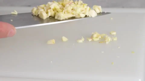 The chef chopping garlic on a white plastic cutting board, close-up view, prepar Stock Footage 287880330