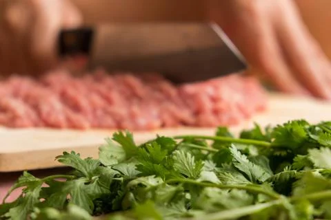Chef is chopping the raw pork on the wooden cutting board with a sharp knife Stock Photos