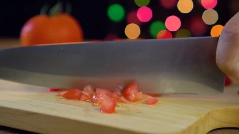 Chef chopping a tomato on cutting board in colour light bokeh background Stock Footage 92087934
