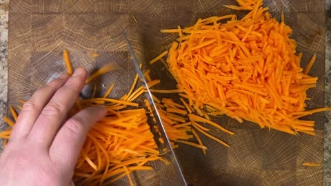 Chef chops chopped carrots with a knife on wooden cutting board. Video stock 302273235