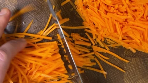 Chef chops chopped carrots with a knife on wooden cutting board. 스톡 동영상 302748899
