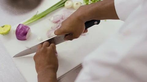 A chef chops red onions next to chopped green onion Stock-Footage 90971016
