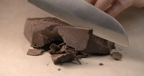 Chef chops of small pieces of chocolate by knife in slow motion, cooking with Stock Footage 118384017