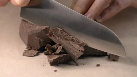 Chef chops of small pieces of chocolate by knife in slow motion Stock Footage 143776867