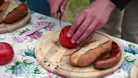 Chef chops tomatoes to make a hot dog Stock Footage 137828108