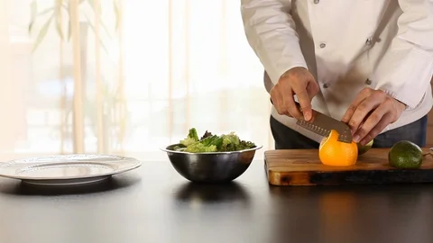 The chef is cleaning the orange with a knife.there's an mango on the table, an Stock Footage 115478633
