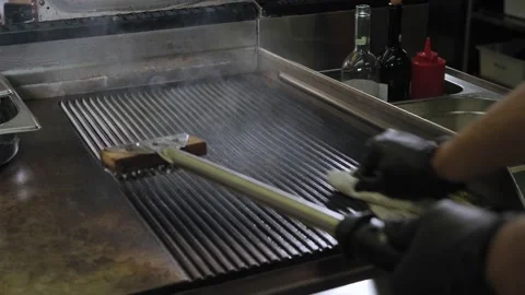 The chef cleans the grill after roasting meat in the restaurant kitchen. Video stock 147398770