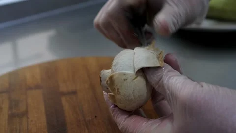 Chef cleans the mushroom with a knife. Close-up of gloved hands. Stock Footage 131507708