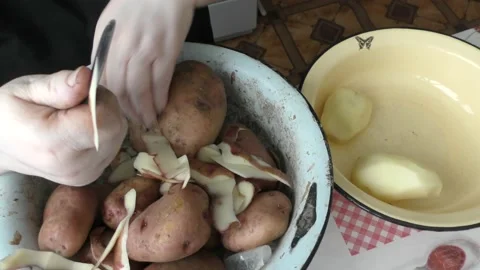 Chef cleans raw potatoes with a knife Stock Footage 177159777