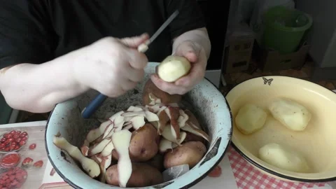 Chef cleans raw potatoes with a knife Stock Footage 177161125
