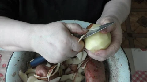 Chef cleans raw potatoes with a knife Stock Footage 197931327