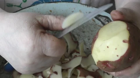 Chef cleans raw potatoes with a knife Stock Footage 202107585